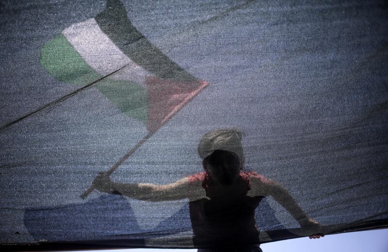 epaselect epa06877784 A boy waves the Palestinian flag sailing in fishing boats carrying a group of activists during a protest against the Israeli siege imposed on Gaza Strip, west of Gaza City, 10 July 2018. According to media reports, a boat carrying students, wounded, and dual nationals in a symbolic attempt to break the Israeli blockade imposed for more than a decade, but was intercepted by the Israeli navy in the Mediterranean.  EPA/HAITHAM IMAD