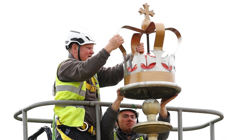 Workers place a decorative crown at the top of a flag pole facing Buckingham Palace. Reuters