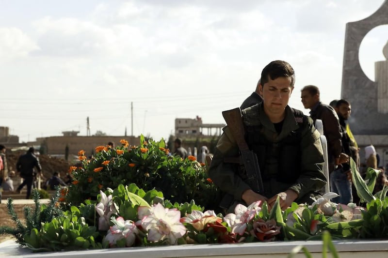 A man mourns next to a grave at a cemetery in the north-eastern Syrian city of Qamishli during the funeral on February 28, 2016, of a member of the Kurdish internal security forces who was reportedly killed the day before in Tal Abyad. Delil Souleiman / AFP