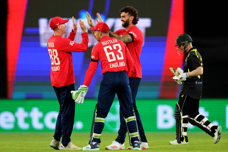 England's Reece Topley, centre, celebrates taking the wicket of Australia's David Warner, right, with teammates. AFP