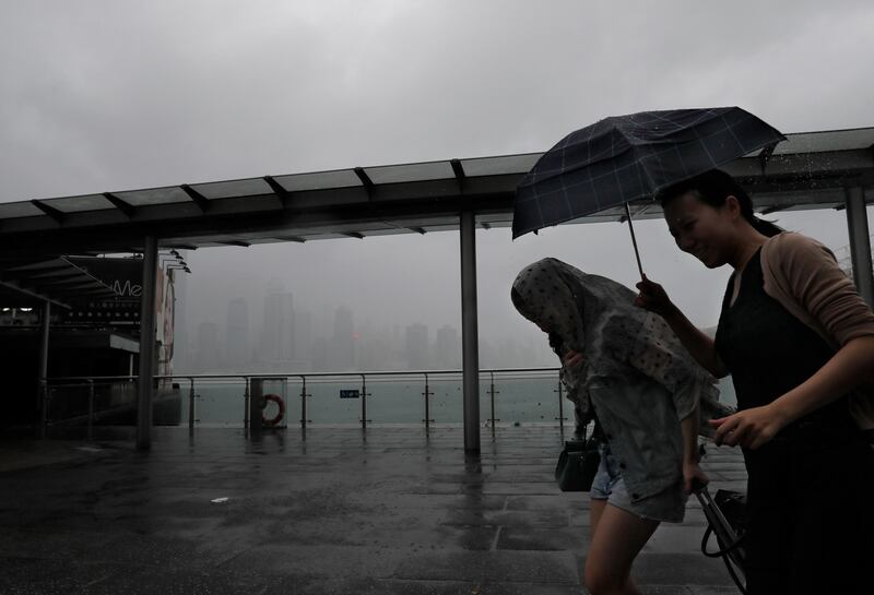 People walk against the strong wind caused by tropical storm Pakhar on the waterfront of Victoria Habour in Hong Kong. Vincent Yu / AP Photo