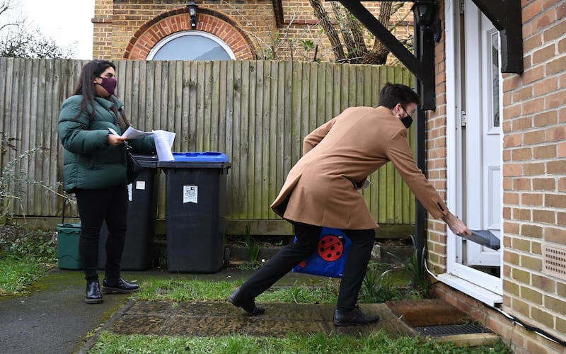 Volunteers go door-to-door delivering Covid-19 home test kits in Woking, Britain.  EPA