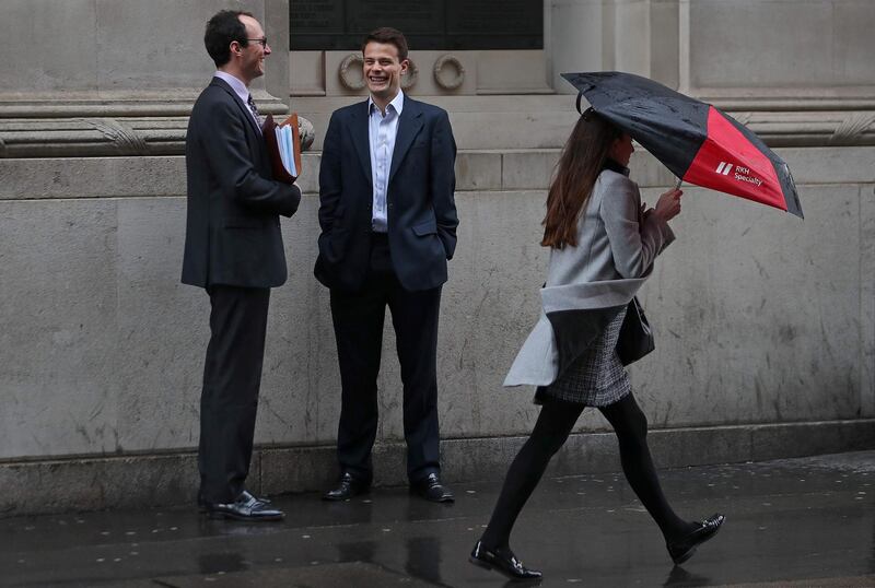 A woman shelters from the rain beneath an umbrella as she walks past talking men in the City of London on April 4, 2018.
Employers with more than 250 staff have until midnight on Wednesday to publish the gender pay gap within their companies. Britain's Prime Minister Theresa May is eager to see a change in the gender gap, or percentage difference between the average male salary and the average female salary -- in an eventual push toward pay equality, meaning the same money for a comparable job. / AFP PHOTO / Daniel LEAL-OLIVAS