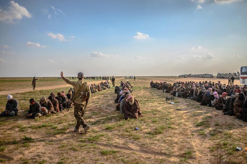 TOPSHOT - Men suspected of being Islamic State (IS) fighters wait to be searched by members of the Kurdish-led Syrian Democratic Forces (SDF) after leaving the IS group's last holdout of Baghouz, in Syria's northern Deir Ezzor province on February 22, 2019.   / AFP / Bulent KILIC
