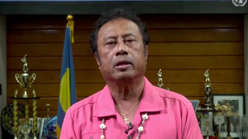 Tommy Esang Remengesau Jr., President of Palau, sports a pink polo shirt and adorns his office with awards during a pre-recorded message to the 75th session of the United Nations General Assembly. UNTV via AP