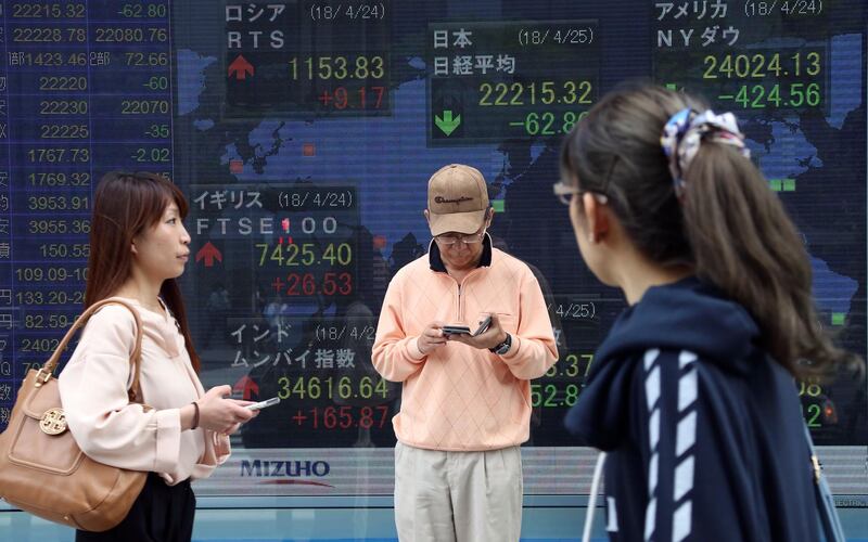People walk by an electronic stock board of a securities firm in Tokyo, Wednesday, April 25, 2018. Asian shares dipped Wednesday, mirroring a sell-off on Wall Street on worries over slowing growth and falling profits. (AP Photo/Koji Sasahara)