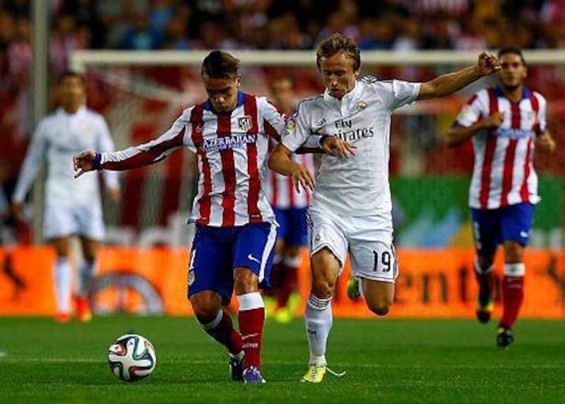 Atletico Madrid's Antoine Griezmann, left, and Real Madrid's Luka Modric fight for the ball during their Spanish Super Cup second leg soccer match at Vicente Calderon stadium in Madrid August 22, 2014. REUTERS/Sergio Perez