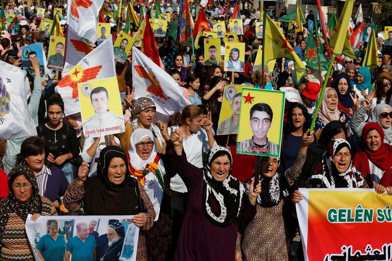 Kurdish and Arab protesters chant slogans against Turkish President Tayip Erdogan as they walk during a march to the United Nations Headquarters in the town of Qamishli, Syria. REUTERS