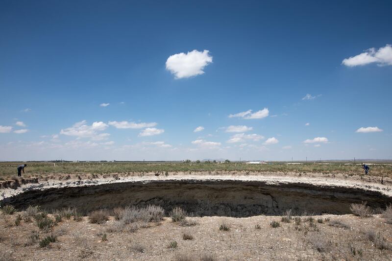 Geologists Arif Delikana, left, and Fetullah Arik inspect a sinkhole near Karapinar.