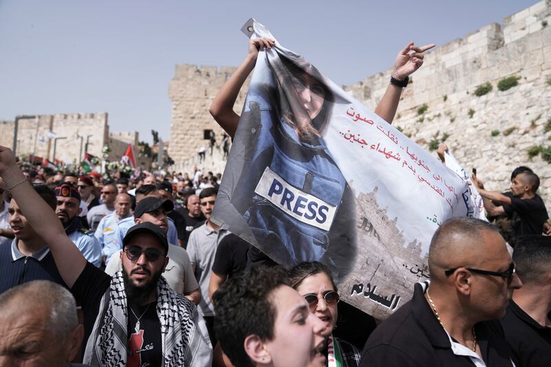 Mourners hold a banner with a photo of Abu Akleh as they walk from the Old City of Jerusalem to her burial site. AP