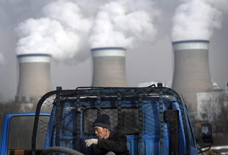 A worker throws his cigarette while smoking on a truck parked in front of a cooling towers of a coal-fired power plant in Datong, Shanxi province, China. AP Photo