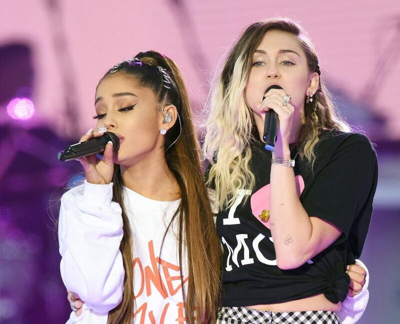 Singers Ariana Grande, left, and Miley Cyrus perform. Dave Hogan via AP