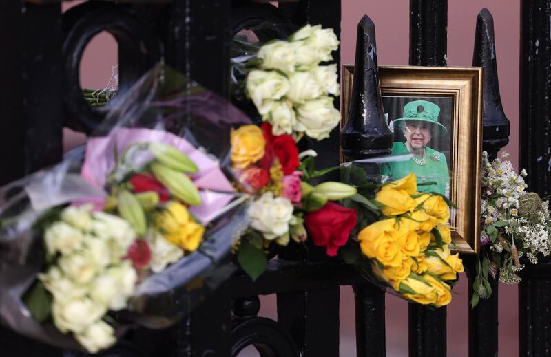 Floral tributes and a portrait of Queen Elizabeth on the gates of Buckingham Palace in London. EPA