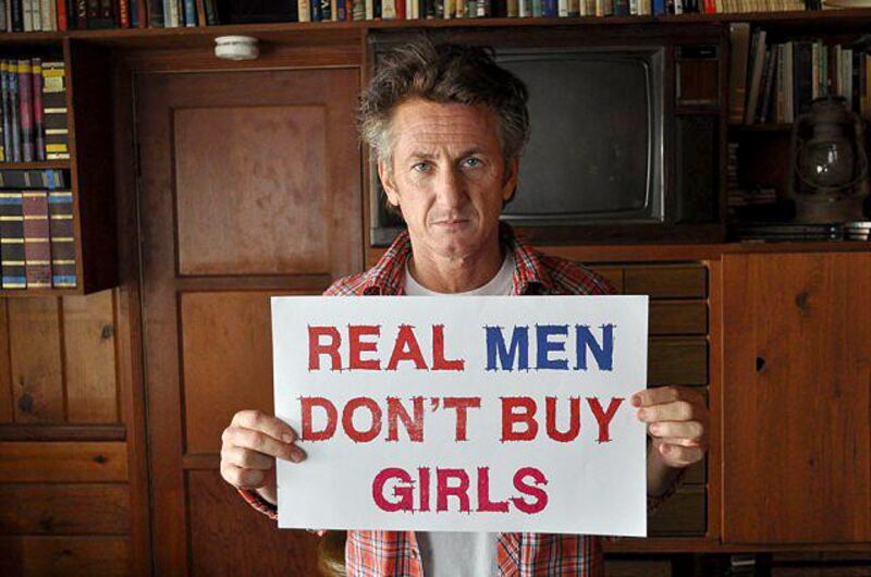 Sean Penn holds up a Real Men Don’t Buy Girls sign. Courtesy Sean Penn