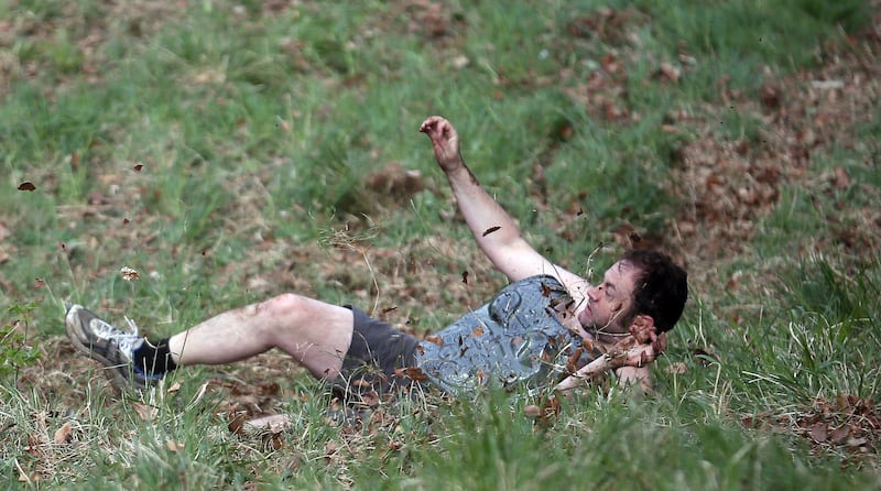 BROCKWORTH, ENGLAND - MAY 27:  A man falls down the steep gradient of Cooper's Hill during the annual Bank Holiday tradition of cheese-rolling on May 27, 2013 in Brockworth, Gloucestershire, England. Although no longer a officially organised event since 2009, thousands of spectators still gathered to watch contestants from around the world tumbling down the 200m slope, which has a 1:1 gradient in parts, in a series of races that are said to date back hundreds of years, with the winner of each receiving a cheese. Injuries such as broken arms and legs are commonplace.  (Photo by Matt Cardy/Getty Images) *** Local Caption ***  169553495.jpg