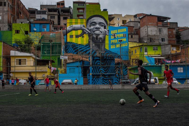 Children play football in front of the graffiti mural of Brazilian striker Gabriel Jesus in Sao Paulo, Brazil. The painting was done by a group of artists to pay homage to the player who grew up in the area, the Jardim Peri neighbourhood that is one of the poorest neighbourhoods in the city. Victor Moriyama / Getty Images