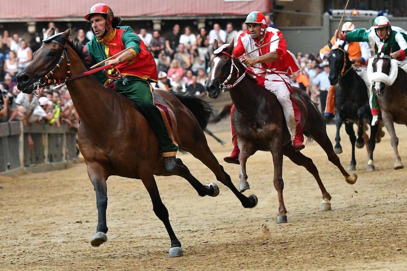 Andrea Mari, a jockey representing the Drago contrada, or Dragon district, races on his horse Rocco Nice during the Palio di Siena. Vincenzo Pinto / AFP