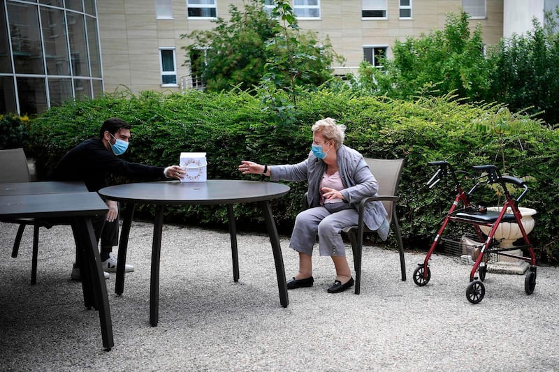 An elderly woman receives a gift from her grandson on Mother's Day in Saint-Maur-des-Fosses, near Paris.  AFP