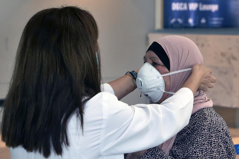 A healthcare worker adjusts the mask of a passenger who is departing the Rafik Hariri International Airport in Beirut, Lebanon, Wednesday, July 1, 2020. AP