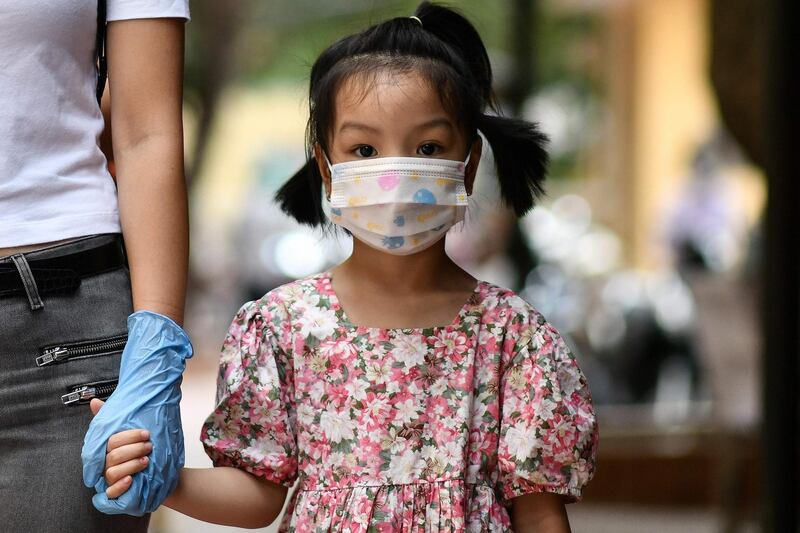 A young girl holds her mother's hand while waiting to be tested at a makeshift rapid testing centre in Hanoi , Vietnam.  AFP
