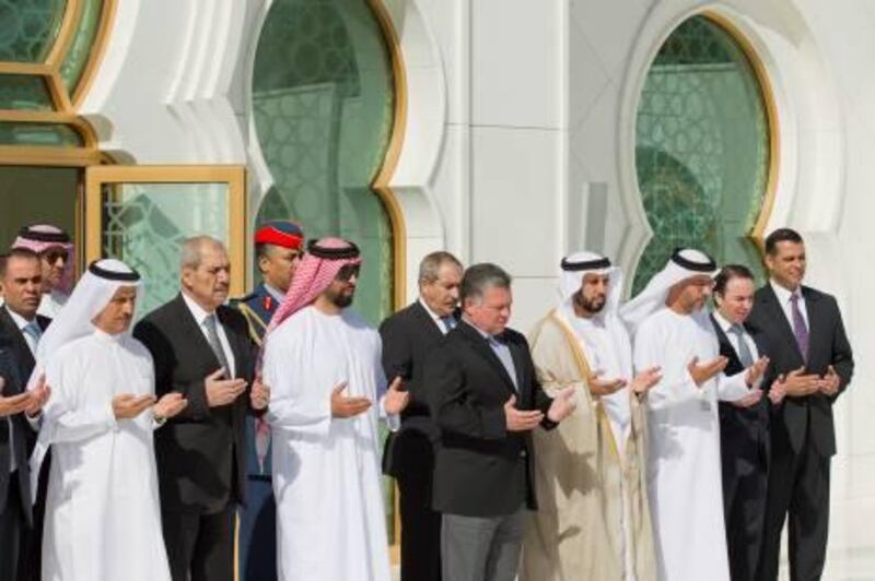 ABU DHABI, UNITED ARAB EMIRATES - February 4, 2013: HE Sultan bin Saeed Al Mansouri UAE Minister of Economy (L), HH Sheikh Tahnoon bin Zayed Al Nahyan Chairman of Amiri Aviation (3rd L), His Majesty King Abdullah II bin Al-Hussein King of Jordan (4th L), and others pray over the tomb of the late Sheikh Zayed bin Sultan Al Nahyan, founding President of the United Arab Emirates (NOT SHOWN), at the Sheikh Zayed Grand Mosque. .( Ryan Carter / Crown Prince Court - Abu Dhabi ).---.