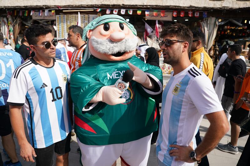 Argentina fans are interviewed by a person in a Mexico costume, in the souq area of Doha. PA