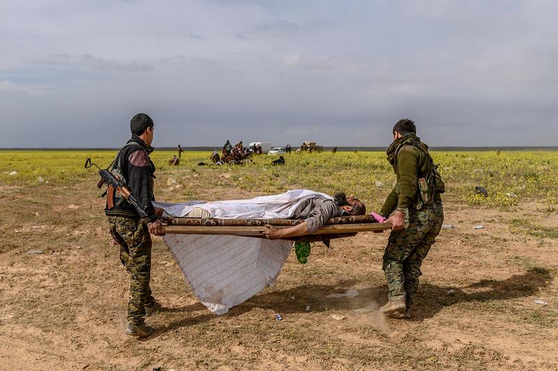 Members of the Kurdish-led Syrian Democratic Forces (SDF) carry a suspected ISIS fighter out on a stretcher. AFP