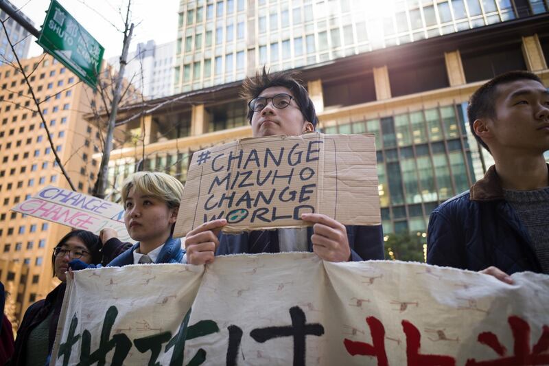 A group of youth climate activists hold up a protest banner and placards outside the Mizuho Financial Group Inc. headquarters in Tokyo, Japan, on Friday, March 6, 2020. The anti-coal demonstration organized by Fridays for Future Tokyo denounced Mizuho Bank's role in financing coal projects globally. Photographer: Kentaro Takahashi/Bloomberg