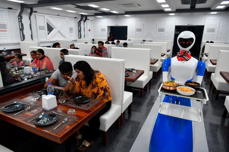 A service robot carries food in a tray for customers on the opening day of the "Robot" restaurant in Bangalore on August 17, 2019. The restaurant has introduced one usher and five robots to interact and serve its customers food. / AFP / Manjunath Kiran
