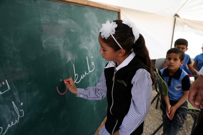 A child writes 'Palestine' on board at tent classroom of school for Bedouin pupils on the third day of the school year, at Am Kusa Bedouin community, south of the West Bank city of Hebron. EPA