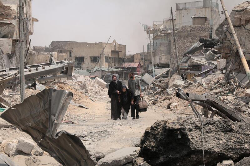 A family walks past the destroyed Al Nuri Mosque as they struggle to muster the energy to escape the old city, where heavy fighting and an intense bombardment is exacting a high toll on civilians. Florian Neuhof / The National