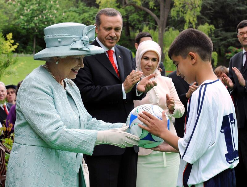 Queen Elizabeth accompanied by Turkish Prime Minister Recep Tayyip Erdogan gives a David Beckham-signed football to a Turkish boy at a garden party held for her birthday at the British Embassy in Ankara in May 2008. Getty Images