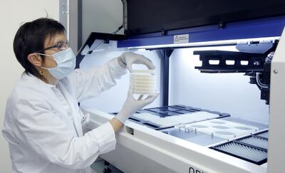 An employee of Swiss biotechnology company Molecular Partners takes samples out of a colony picker robot in a laboratory at the company's headquarters in Schlieren, Switzerland August 11, 2020. REUTERS/Arnd Wiegmann