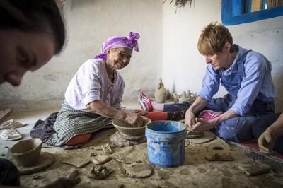 Moroccan potter Aicha Tabiz (L), also known as Mama Aicha, sits next to British apprentice Kim West (R), 33, during a pottery workshop near the village of Ourtzagh in the foothills of the Rif mountains on June 12, 2019. Beautiful handcrafted pottery made by Mama Aicha rarely sells in Morocco anymore, but thanks to social media her ancient techniques are drawing students from around the world. / AFP / FADEL SENNA
