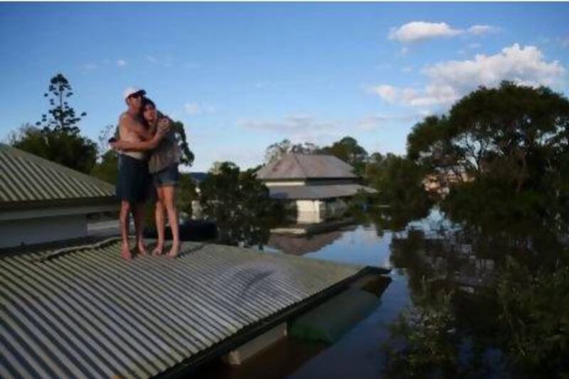 A man comforts his daughter on their roof in the town of Bundaberg as parts of southern Queensland experiences record flooding in the wake of ex-tropical Cyclone Oswald.