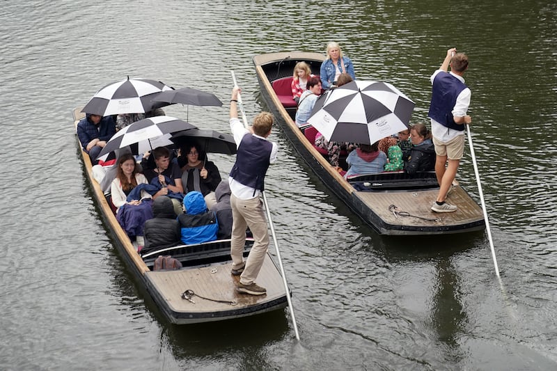 Punt passengers shelter from the drizzle on the River Cam in Cambridge