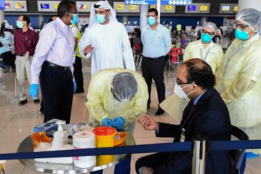 Health workers test an Indian citizen at Dubai International Airport before he boards a repatriation flight. AFP  