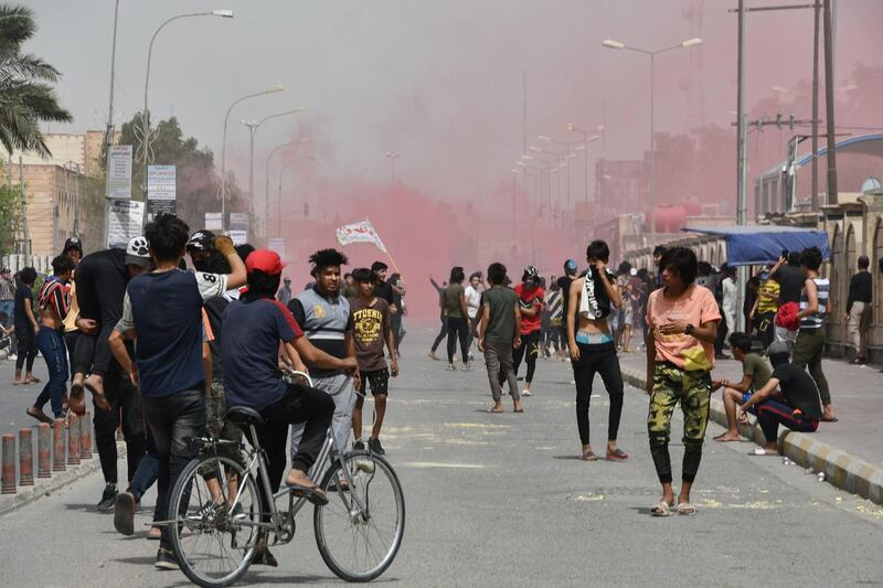 Iraqi protesters flee smoke grenades fired by security forces amid clashes following an anti-government demonstration in Iraq's southern city of Nasiriyah in Dhi Qar province.  AFP