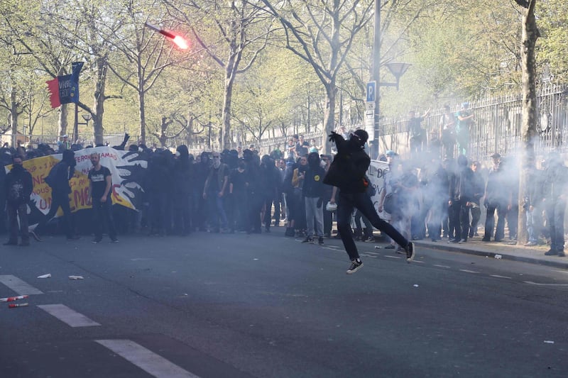 TOPSHOT - A protester throws a burning flare during clashes with police at a demonstration on April 19, 2018, in Paris, as part of a multi branch day of protest called by French unions CGT and Solidaires against the French president's policies amid a rail strike and spreading student sit-ins.
France's president faced mass protests on April 19 as trade unionists seek to galvanise angry students, public sector workers and striking train drivers into a joint movement against his multi-pronged drive to overhaul the French economy. / AFP PHOTO / Zakaria ABDELKAFI