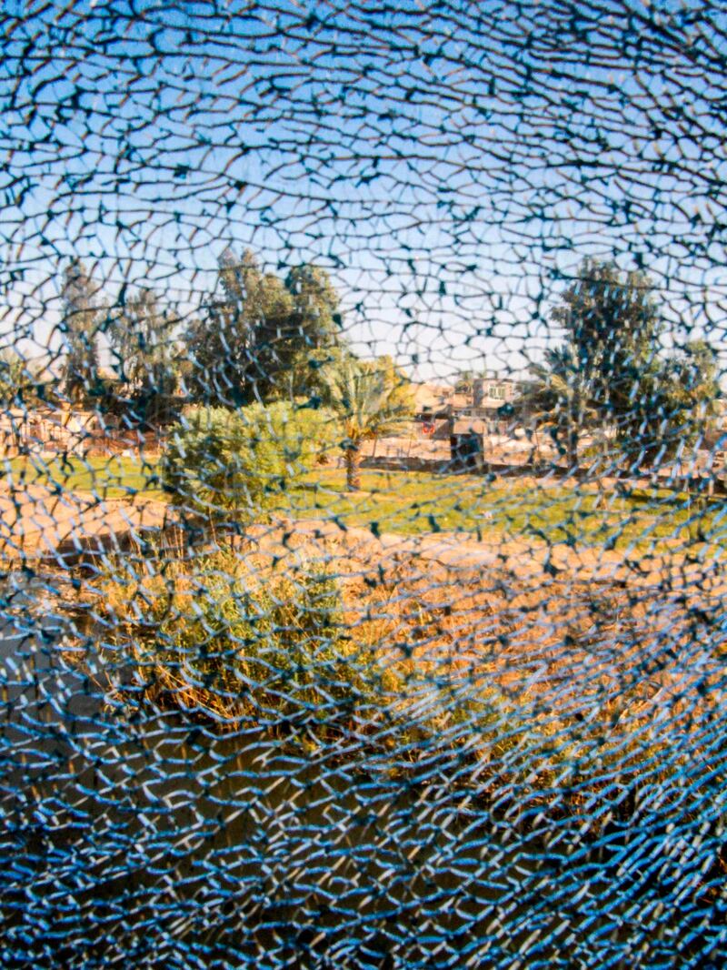 A picture taken on August 19, 2018 shows the view through a broken window on the train from the Iraqi capital Baghdad to the city of Fallujah in Anbar province, about 70 kilometres west. - The train connecting Baghdad to Falluja, crosses the landscapes of western Iraq through car cemeteries, charred tanks and collapsed buildings. AFP