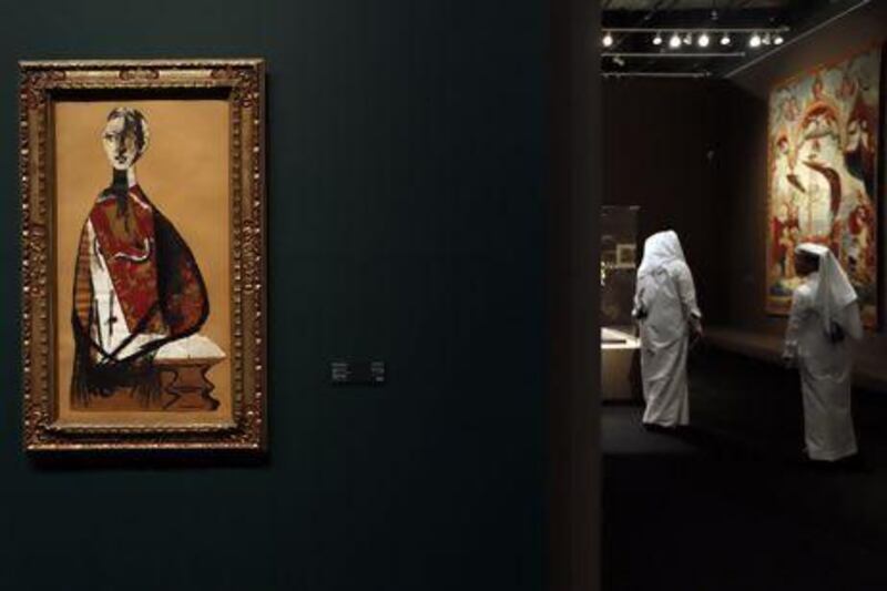 Visitors walk past Portrait of a Lady, by Picasso and The Subjected Reader, a painting by Rene Magritte. AFP.