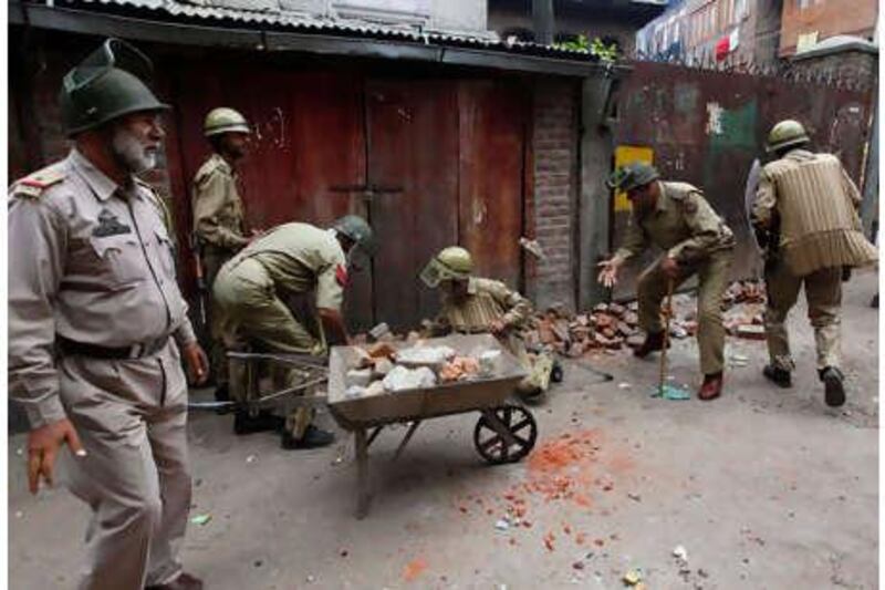 Indian policemen clear away rocks and stones from a road during a protest in Srinagar, India, on Tuesday.