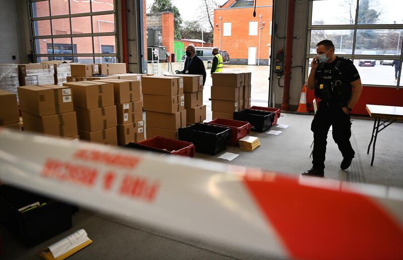A police officer looks over Covid-19 home test kits stored at Woking Fire Station. Door-to-door testing of some eighty thousand people is underway. EPA