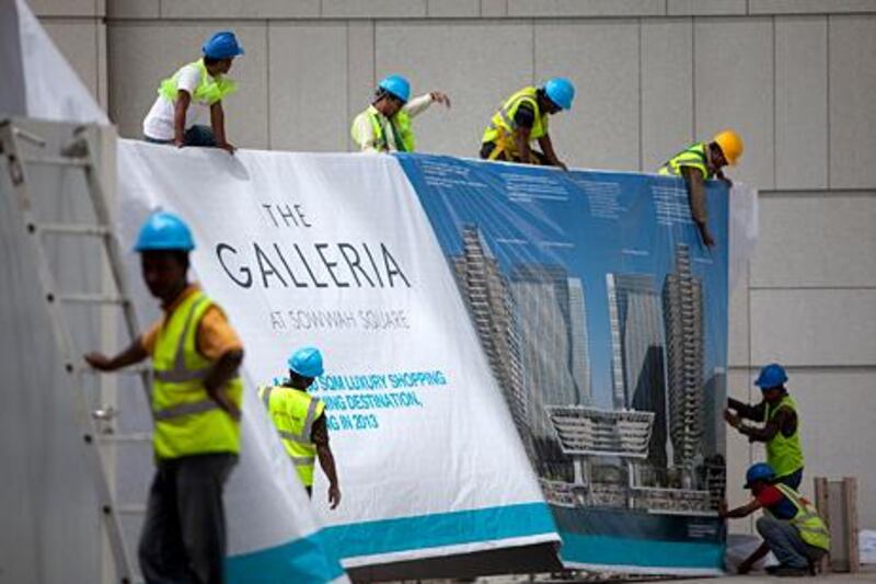United Arab Emirates, Abu Dhabi, April 19, 2012:   
Work and clean-up on Sowwah Square and surrounding construction sites continues at a steady pace on Monday, Apr. 23, 2012, at the Sowwah Island in Abu Dhabi. Here, workers hand a banner for the new Galleria Mall. The island has been renamed Marjan Island. (Silvia Razgova / The National)
