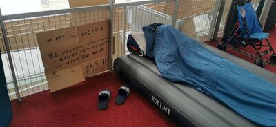 One of the stranded passengers sleeps next to a sign reading "We are from Algeria. 26 persons stuck here." Courtesy RT France