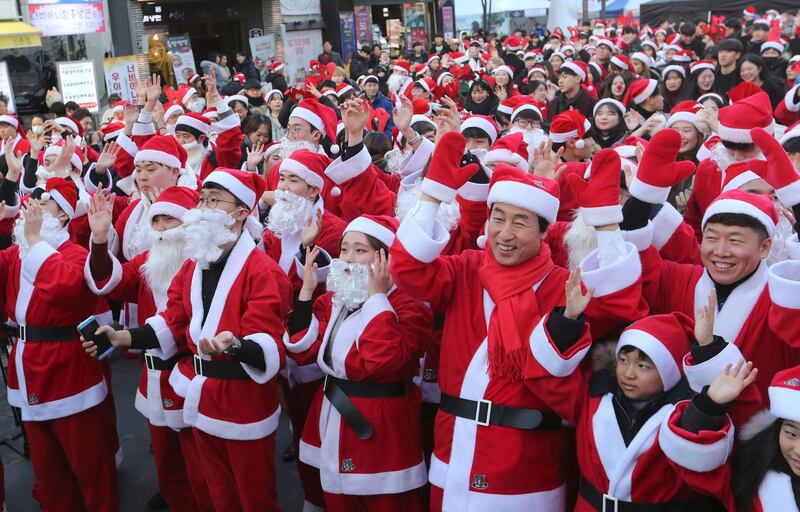 Volunteers clad in Santa Claus costumes perform as they gather to deliver gifts for the poor in downtown Seoul, South Korea, Monday. AP