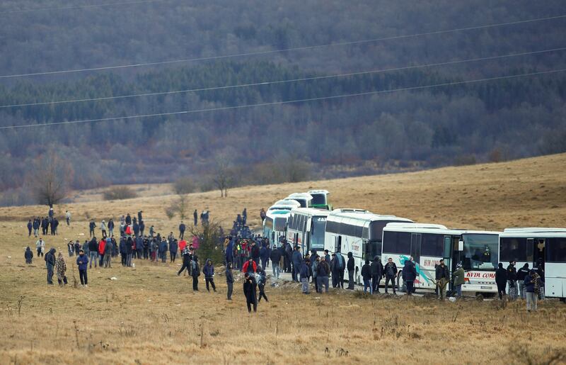 Hundreds of migrants wait near busses. Reuters