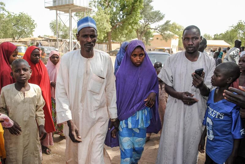 A girl released by Boko Haram walks with his father (L) in Dapchi on March 21, 2018. 
Boko Haram Islamists who kidnapped 110 schoolgirls in Dapchi, northeast Nigeria, just over a month ago have so far returned 101 of the students to the town, the government said today. / AFP PHOTO / -