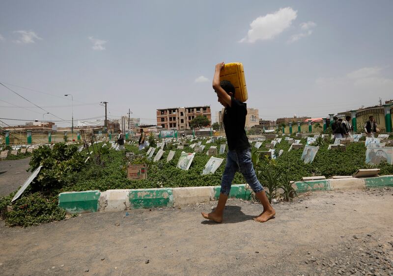 Carrying water past a cemetery dedicated to those killed in the country's ongoing conflict, in Sanaa, Yemen. EPA