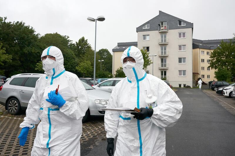 Emergency personnel in protective clothing stand in front of a student dormitory in Koblenz, Germany, Wednesday, July 8, 2020. In three dormitories, residents have contracted Covid-19, others show symptoms. (Thomas Frey/dpa via AP)